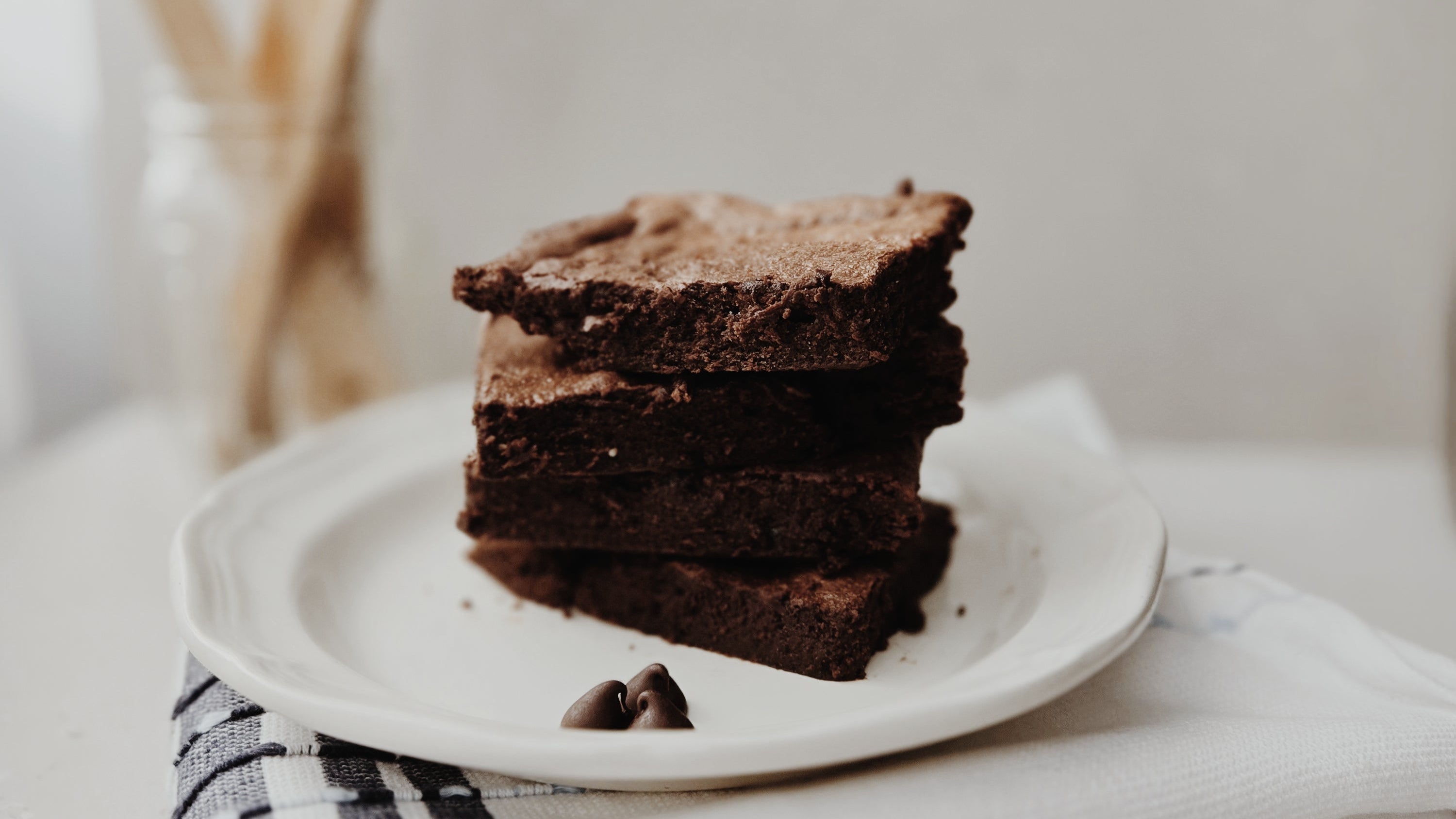 Stack of chocolate brownies on a white plate with a blurred background